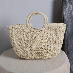 Bolso media luna beige con asas de aro sobre mesa vestida