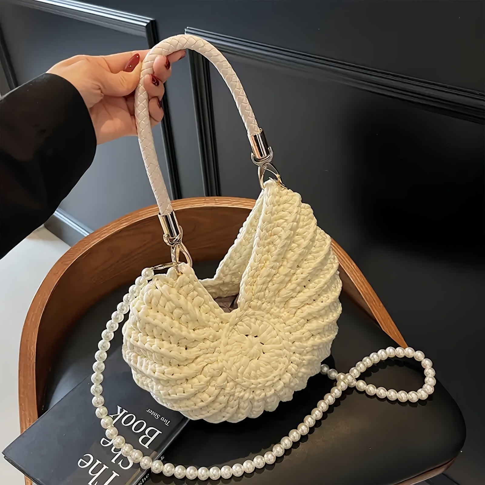 Bolso concha blanco sobre silla negra con la cadena de perlas