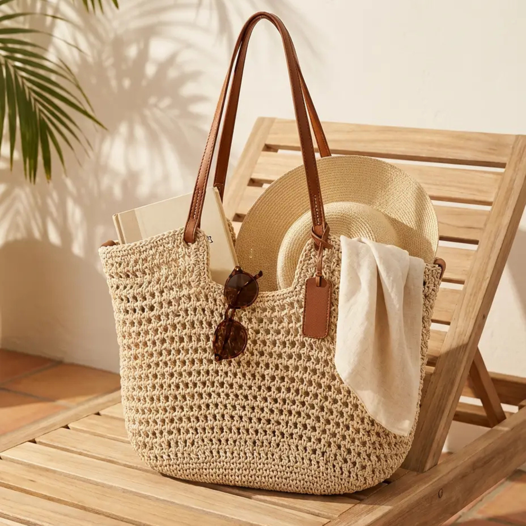 Shopper calada sobre tumbona con sombrero, libro y gafas de sol