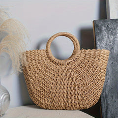 Bolso media luna coñac apoyado junto a jarrón con plumas de pampa