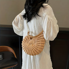 Modelo con vestido blanco llevando el bolso concha con cadena de perlas al hombro