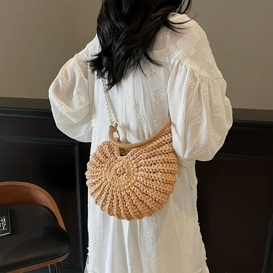 Modelo con vestido blanco llevando el bolso concha con cadena de perlas al hombro