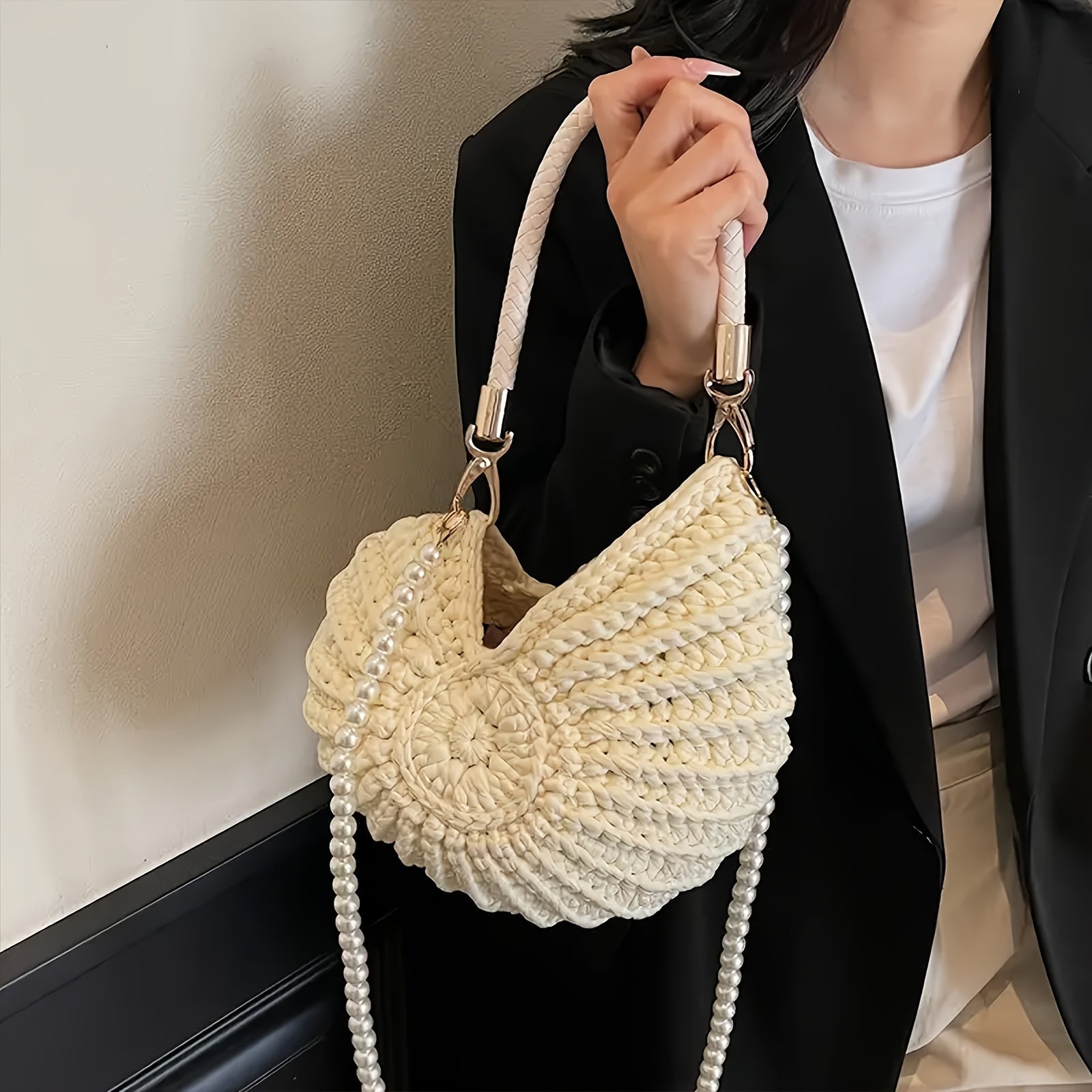 Modelo con blazer negro sosteniendo el bolso concha blanco