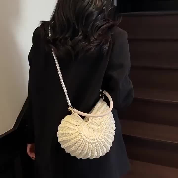 Modelo de espaldas con el bolso concha en bandolera por la cadena de perlas