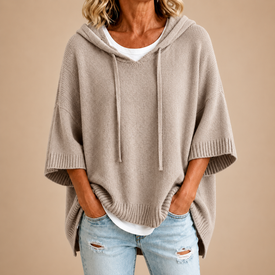 Poncho de punto con capucha en topo, vista frontal sobre fondo beige