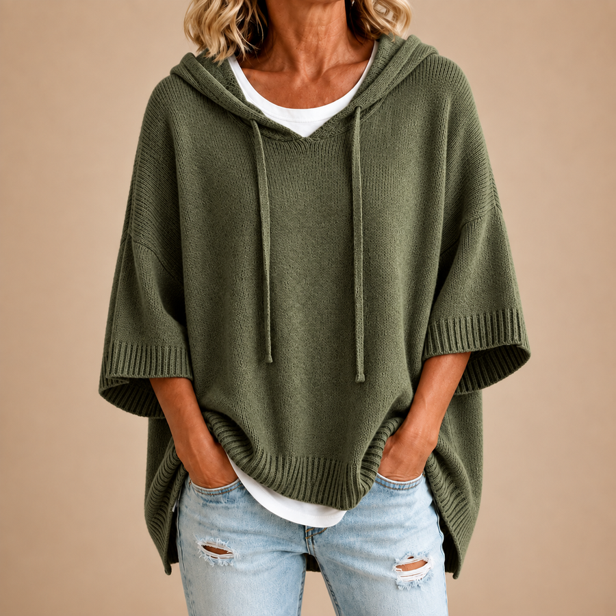 Poncho de punto con capucha en verde militar, vista frontal sobre fondo beige